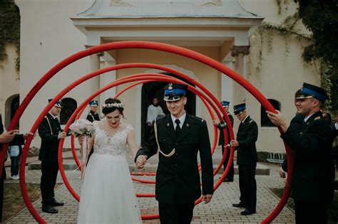 Zdjęcie przedstawiające parę młodą przechodzącą przez szpaler strażacki