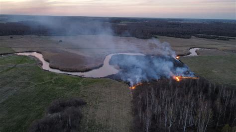zdjęcie przedstawiające skutki pożaru nieużytków, z dymem unoszącym się nad wypaloną ziemią