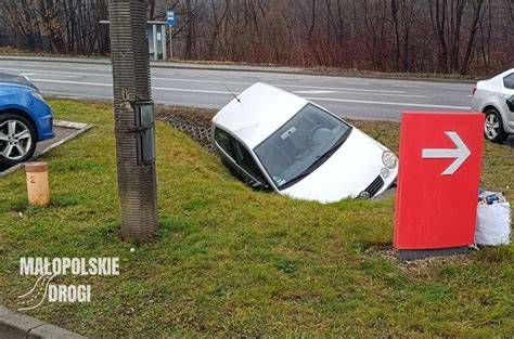 Zdjęcie miejsca dachowania samochodu, widoczne auto w rowie i służby ratunkowe