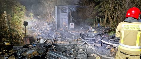 Strażacy gaszący pożar domku letniskowego na terenie ogródków działkowych w nocy