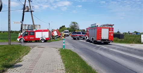 Scena wypadku z przewróconym wozem strażackim i uszkodzonym samochodem osobowym