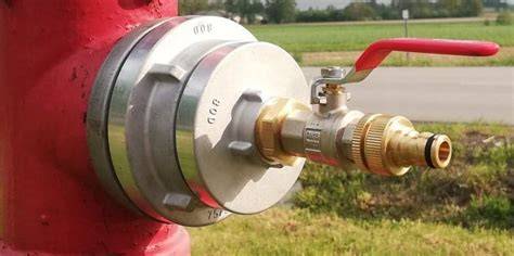 Zdjęcie przedstawiające strażaków podłączających wąż do hydrantu za pomocą redukcji