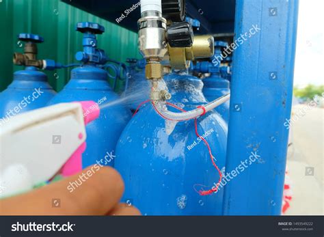 Photo of someone checking a gas cylinder connection with soapy water