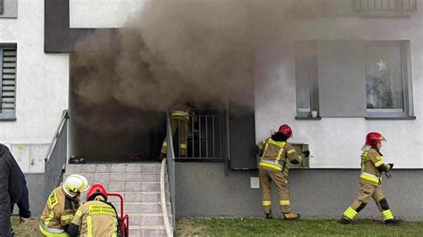 Strażacy gaszący pożar w bloku mieszkalnym, widok z ulicy