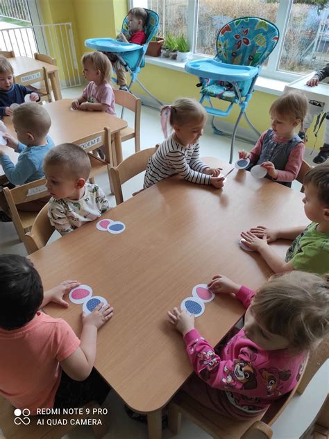 Dzieci siedzące przy niskim stoliku ogrodowym z kolorowymi krzesełkami