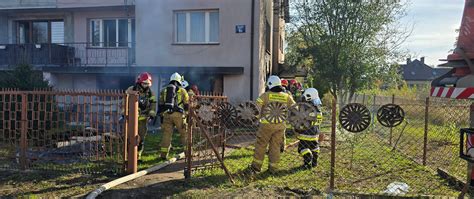 Zdjęcie przedstawiające akcję gaśniczą strażaków w nocy przy zadymionym domu jednorodzinnym