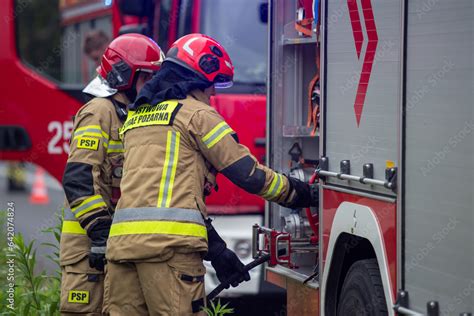 Strażacy rozwijający i podłączający węże strażackie podczas akcji