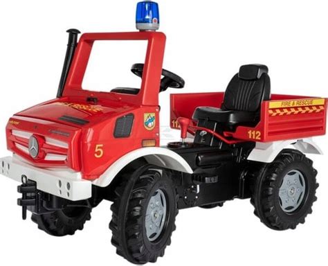 Ilustracja przedstawiająca wóz strażacki Rolly Toys Unimog Mercedes w akcji, z dzieckiem siedzącym za kierownicą.