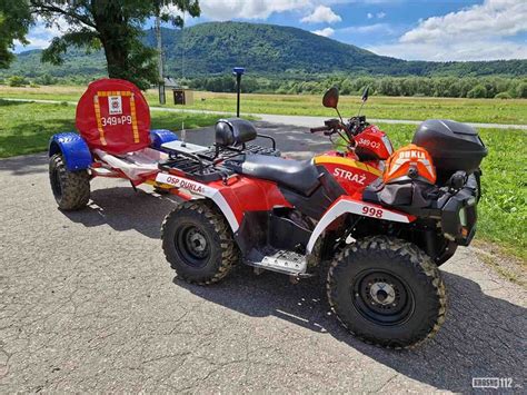 Ilustracja przedstawiająca różne typy pojazdów terenowych używanych przez służby ratownicze, w tym quady, UTV i pick-upy.