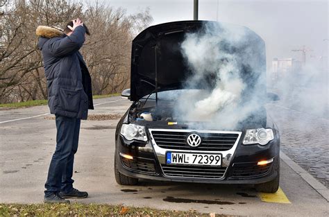 Kierowca używający gaśnicy, dym wydobywający się spod maski samochodu
