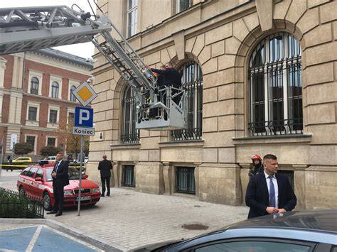 Grafika przedstawiająca ewakuację osób z płonącego budynku za pomocą drabiny