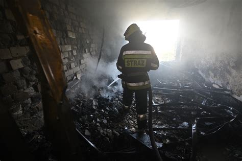 strażacy gaszący pożar, w tle budynek mieszkalny