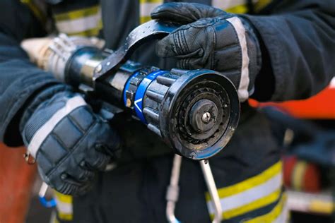 Thematyczne zdjęcie strażaka podłączającego wąż za pomocą redukcji do hydrantu
