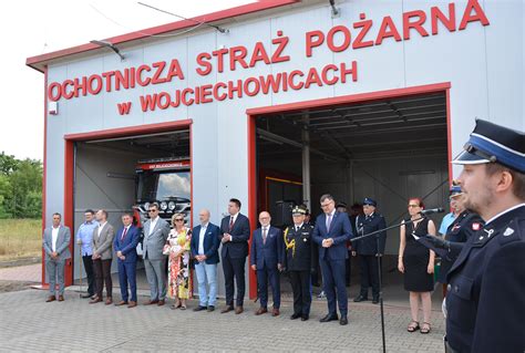 Zdjęcie przedstawiające oficjeli i strażaków podczas ceremonii przekazania samochodu strażackiego OSP Wojciechowice.