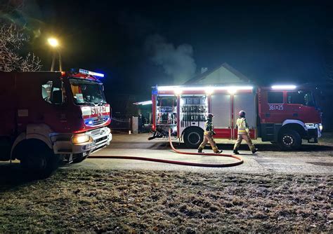 Strażacy gaszą płonący garaż w nocy, w tle widać bliskość budynku mieszkalnego