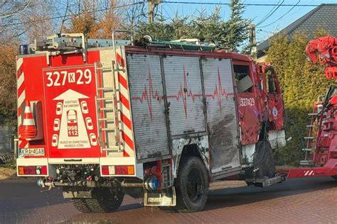 Pojazd częściowo spalony w rowie, strażak dogasza ogień