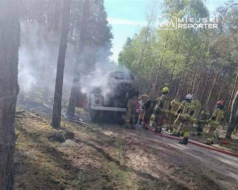 Wóz strażacki podczas gaszenia płonącego samochodu, ujęcie z dystansu