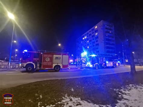 Służby ratownicze prowadzące akcję gaśniczą w budynku wielorodzinnym