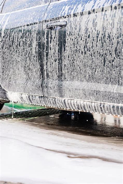 Thematic photo of a car entering a garage on a rainy or snowy day, showing water dripping from the vehicle onto the floor.