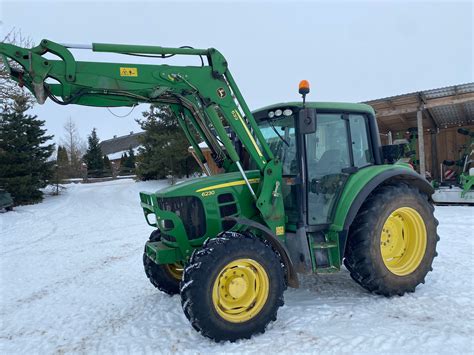 Zdjęcie ciągnika John Deere 6100 z ładowaczem czołowym podczas prac w lesie
