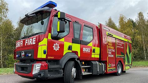 Thematic photo of a modern fire engine in front of a fire station with firefighters