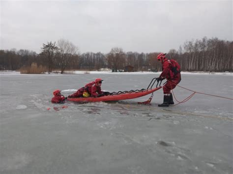 Zdjęcie przedstawiające ratownika w suchym skafandrze podczas akcji ratunkowej na lodzie.