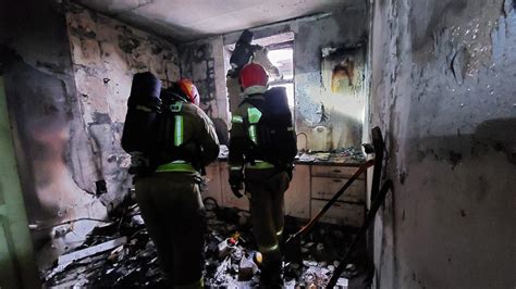 Policjanci gaszący pożar w mieszkaniu przy użyciu wiader