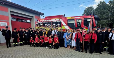 Grupa strażaków i przedstawicieli władz pozuje przed nowym, czerwonym wozem strażackim Renault MDB3 D 4x4.