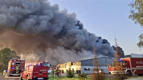 Zdjęcie przedstawiające pożar fabryki w Łodzi, widoczne płomienie i dym, strażacy w akcji