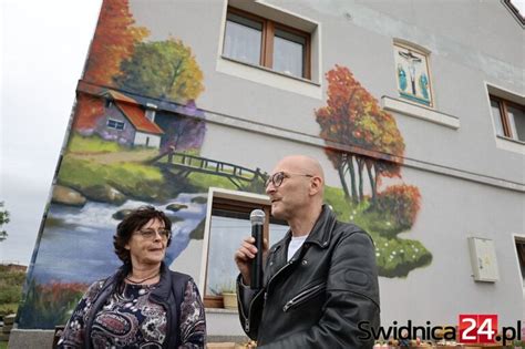 Artysta Robert Kukla malujący mural na bramie remizy OSP Lniano