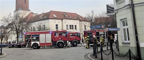 Zdjęcie strażaków przy budynku użyteczności publicznej, z widocznym zadymieniem