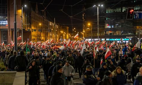 Zdjęcie ilustrujące Marsz Niepodległości z widocznymi transparentami i tłumem uczestników.