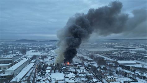 widok z góry na płonącą halę magazynową z dymem unoszącym się nad nią
