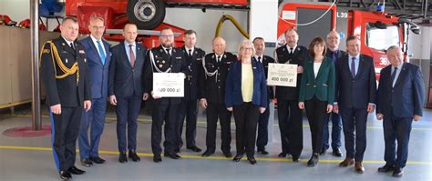 Grupa strażaków z ochotniczych straży pożarnych odbiera promesy na zakup nowych samochodów