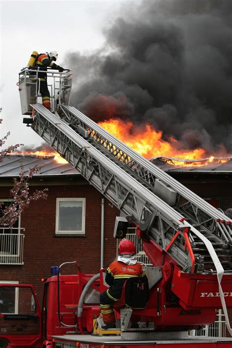 Zdjęcie przedstawiające strażaków gaszących płonący dach budynku mieszkalnego