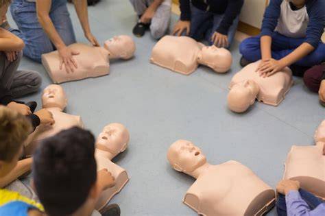 Zdjęcie przedstawiające dzieci uczące się resuscytacji na fantomie lub schemat BLS