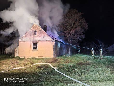 Zdjęcie przedstawiające pożar budynku inwentarskiego nocą, z widocznymi strażakami