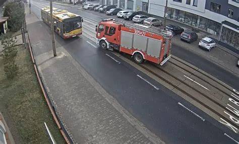 Zdjecie nowoczesnego wozu strazackiego w akcji, z widocznym dymem i strażakami