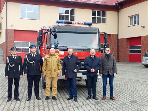 Zdjęcie grupowe strażaków OSP Glinik z nowym samochodem ratowniczo-gaśniczym przed remizą