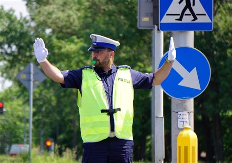 Policjant kierujący ruchem, obok niego nowoczesny polski radiowóz z wyraźną sygnalizacją świetlną.