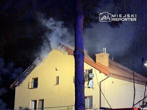 Strażacy gaszący pożar dachu domu jednorodzinnego w nocy