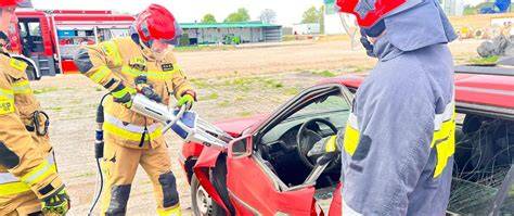Strażacy używający hydraulicznych narzędzi do cięcia karoserii samochodu podczas akcji ratowniczej