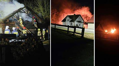 Zdjęcie przedstawiające akcję gaśniczą płonącego drewnianego domu mieszkalnego nocą