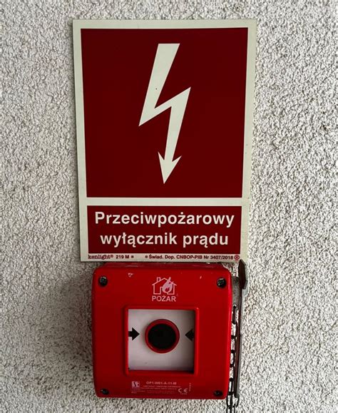 Oznakowanie przeciwpożarowego wyłącznika prądu na czerwonym tle z błyskawicą
