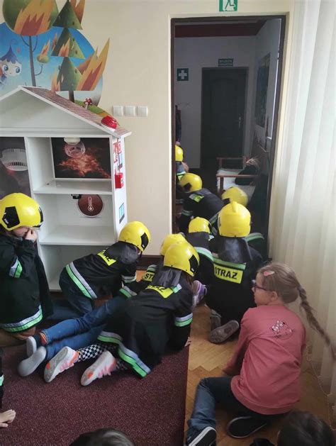 Zdjęcie przedstawiające dzieci uczestniczące w zajęciach edukacyjnych w sali Ognik, uczące się o bezpieczeństwie pożarowym.