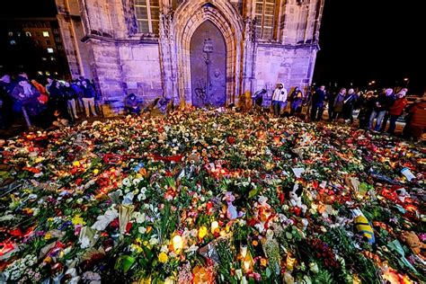 tłum ludzi składający kwiaty i zapalający świece na miejscu pożaru magazynu w Oakland w Kalifornii