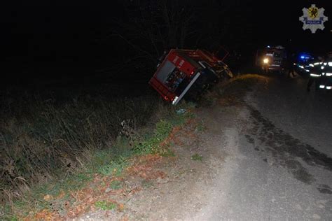 Zdjęcie z miejsca zdarzenia drogowego przedstawiające oświetlony wóz strażacki i uszkodzone pojazdy w warunkach nocnych