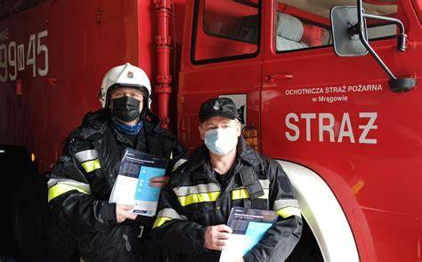 Strażacy OSP kolportujący ulotki informacyjne w społeczności lokalnej