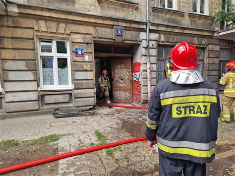 Strażacy w sprzęcie ochronnym wchodzący do zadymionego budynku mieszkalnego